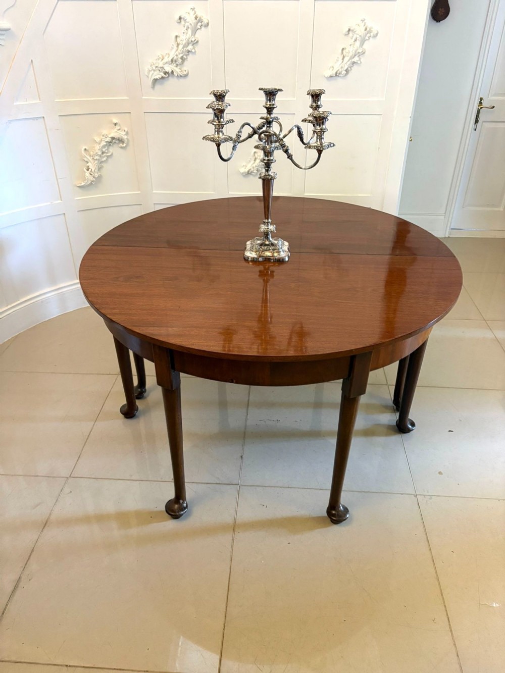 A large extended Georgian mahogany dining table featuring curved D-shaped ends, polished figure top, and slender legs with pad feet. View II