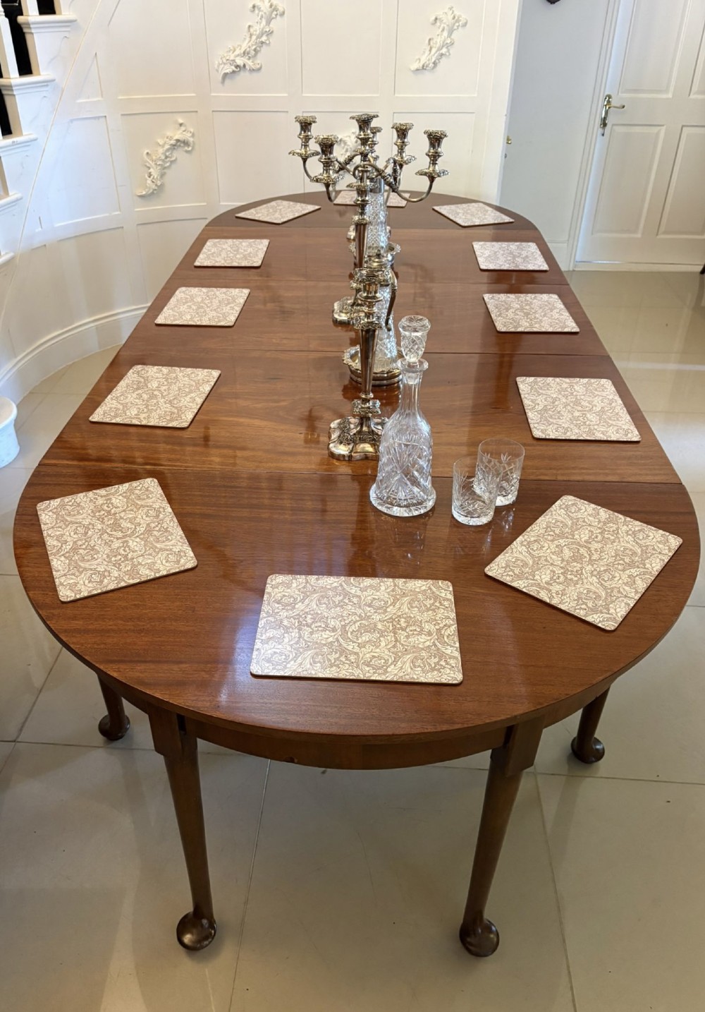 A large extended Georgian mahogany dining table featuring curved D-shaped ends, polished figure top, and slender legs with pad feet. View VI