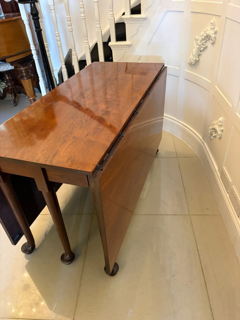 A large extended Georgian mahogany dining table featuring curved D-shaped ends, polished figure top, and slender legs with pad feet. View VII