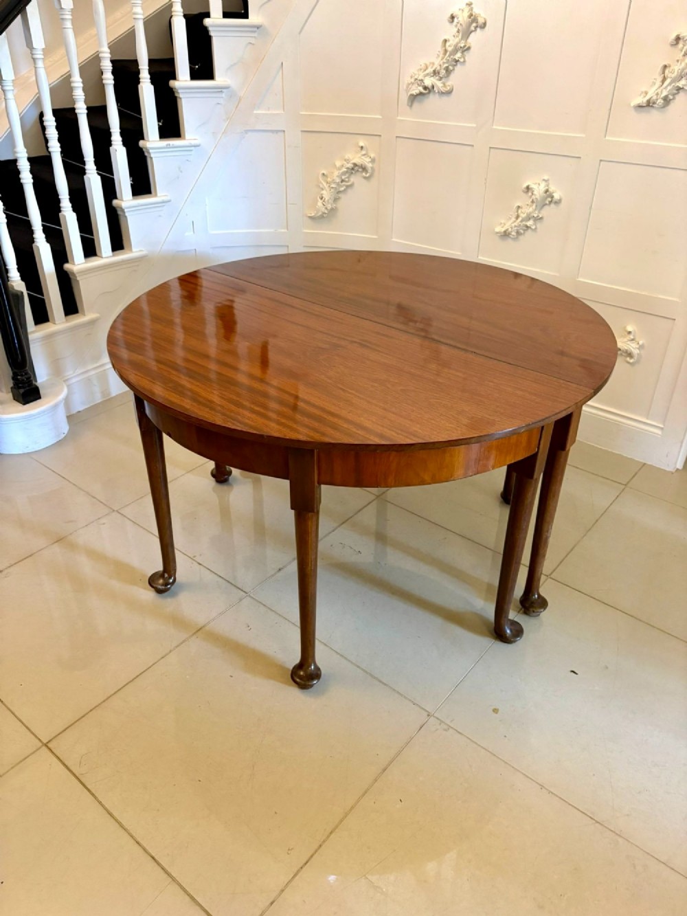 A large extended Georgian mahogany dining table featuring curved D-shaped ends, polished figure top, and slender legs with pad feet. View VIII