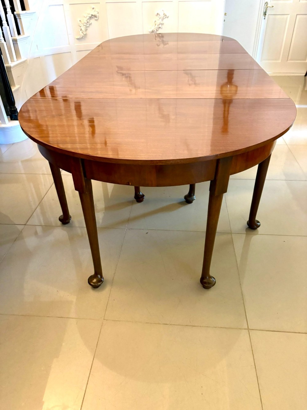A large extended Georgian mahogany dining table featuring curved D-shaped ends, polished figure top, and slender legs with pad feet. View IX