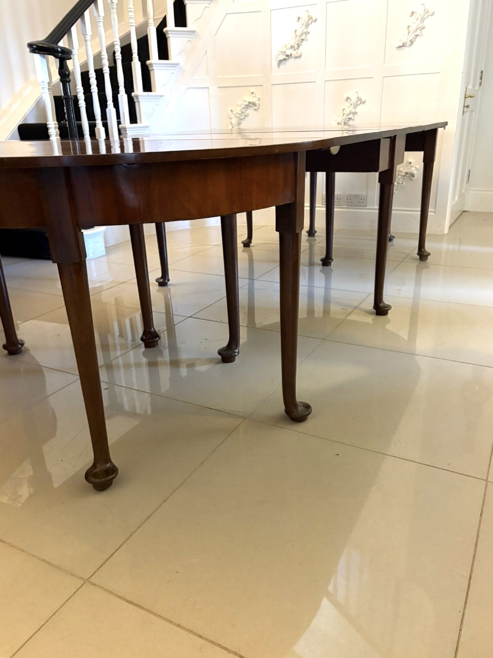 A large extended Georgian mahogany dining table featuring curved D-shaped ends, polished figure top, and slender legs with pad feet. View X