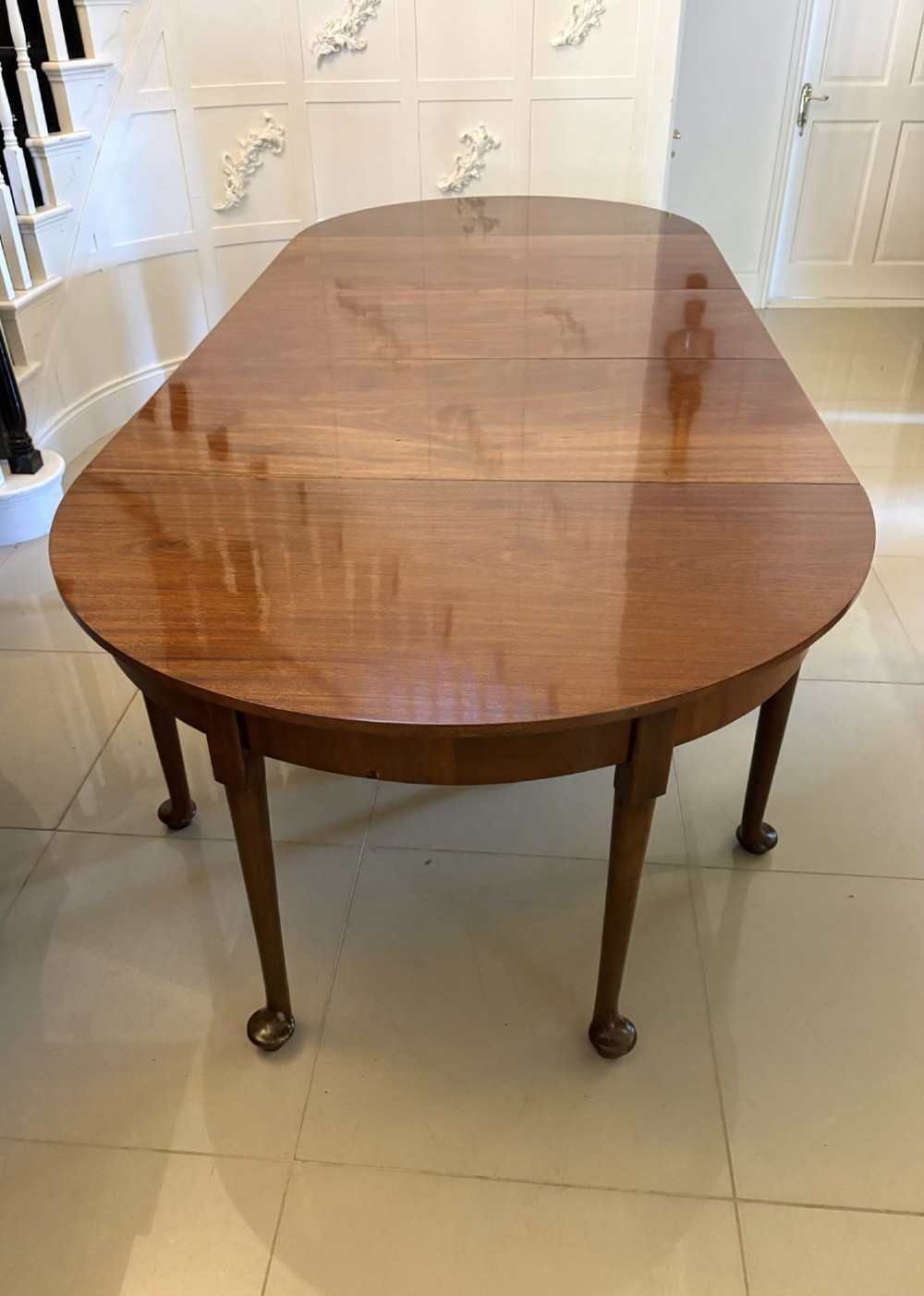 A large extended Georgian mahogany dining table featuring curved D-shaped ends, polished figure top, and slender legs with pad feet.