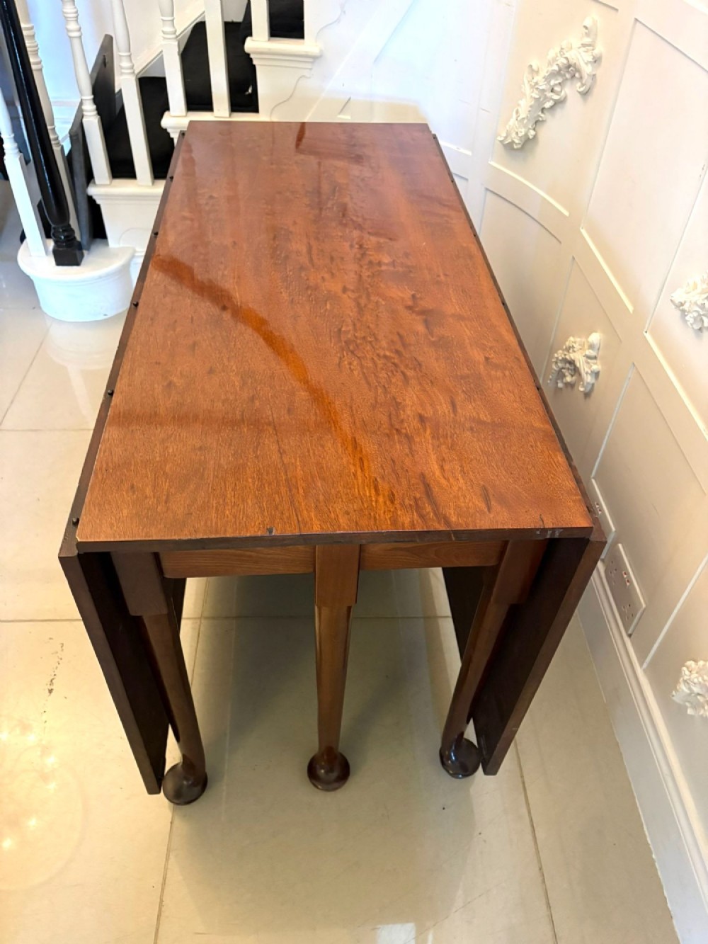 A large extended Georgian mahogany dining table featuring curved D-shaped ends, polished figure top, and slender legs with pad feet. View XII