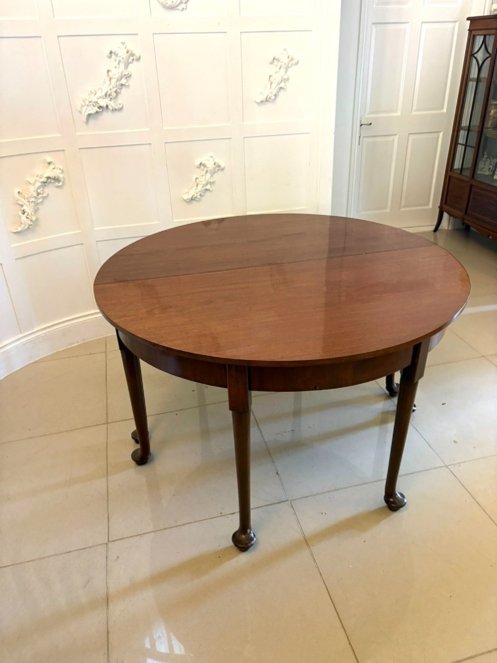 A large extended Georgian mahogany dining table featuring curved D-shaped ends, polished figure top, and slender legs with pad feet. View XIV