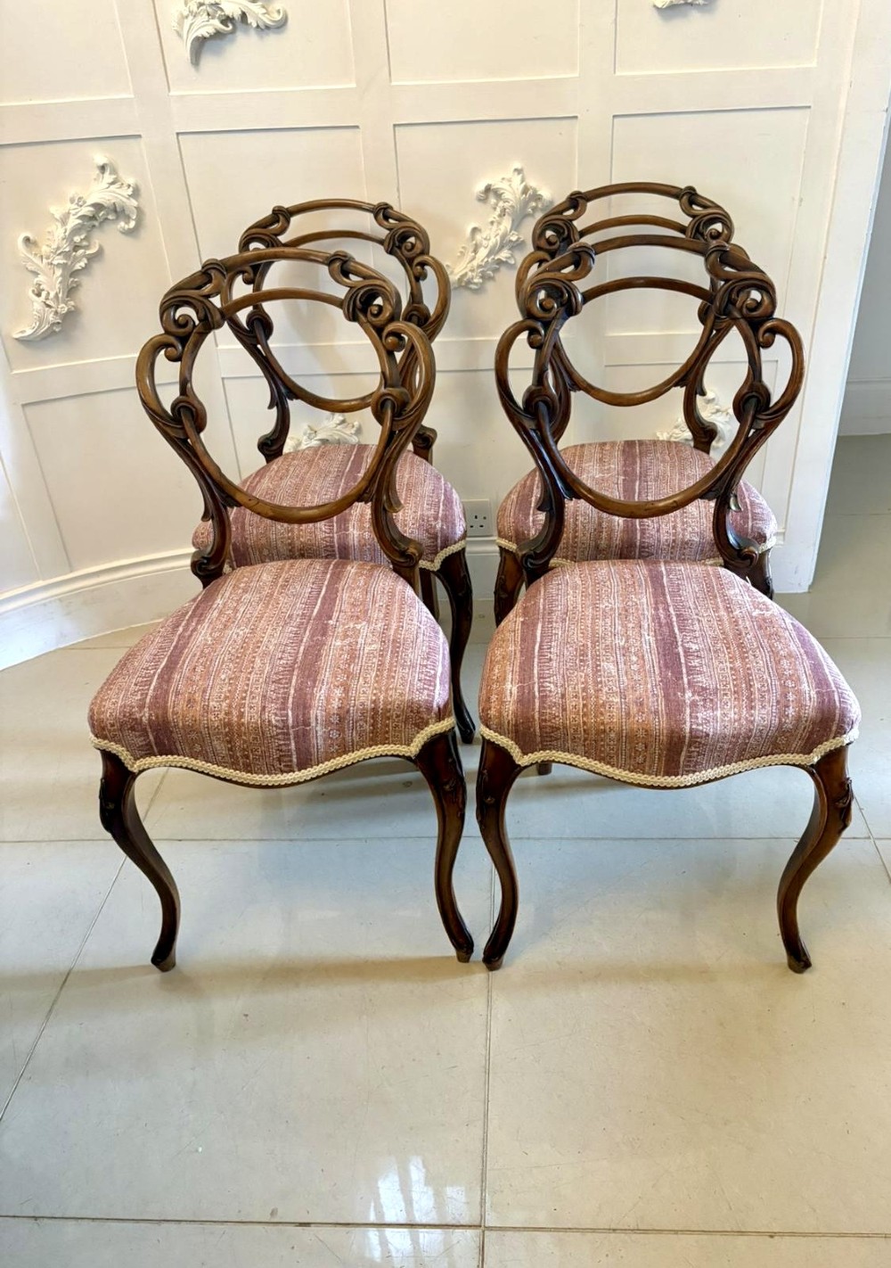 A set of four Victorian walnut balloon back dining chairs featuring carved openwork backrests, cabriole front legs, and patterned rose-coloured upholstered seats. View II