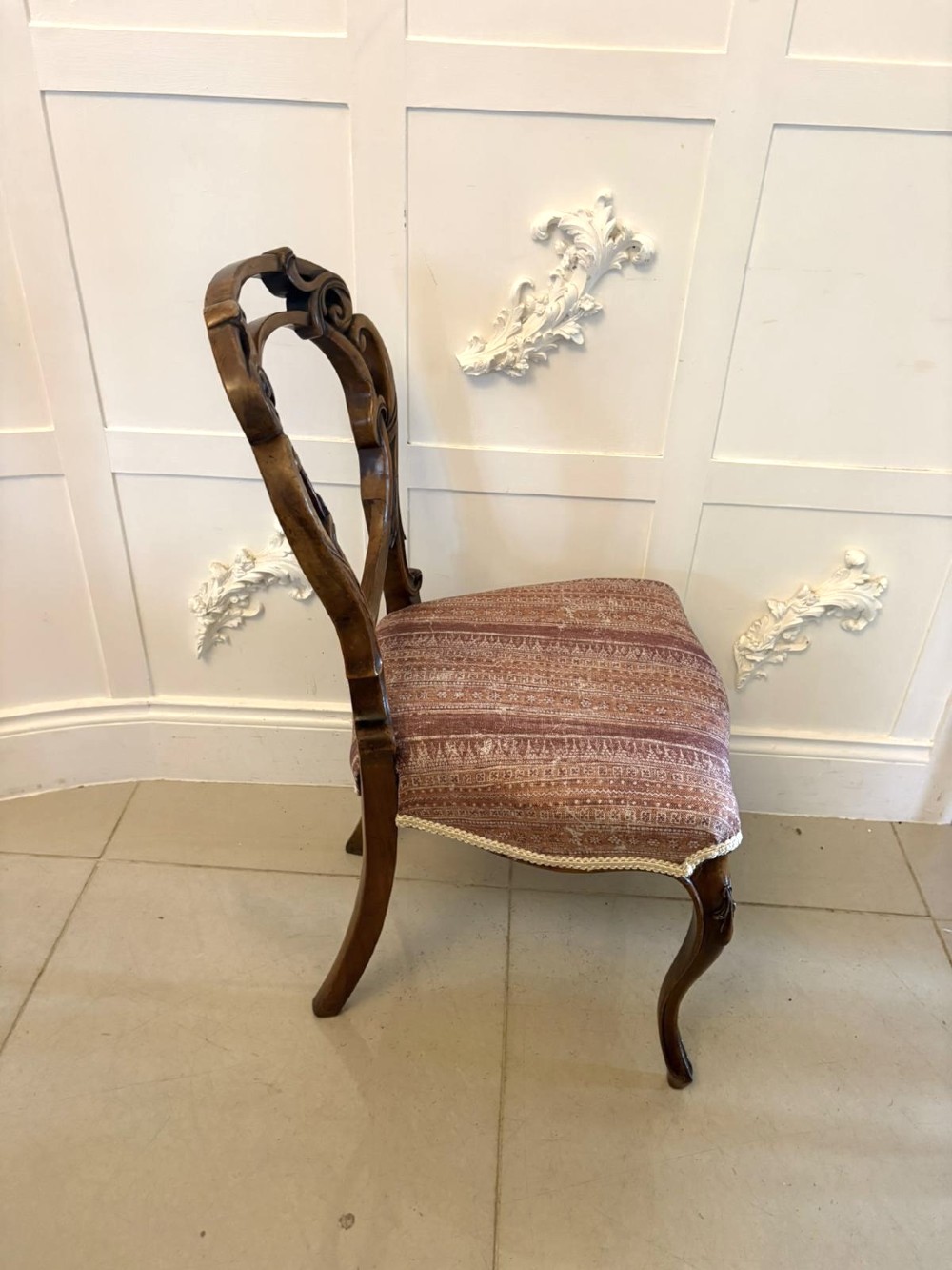 A set of four Victorian walnut balloon back dining chairs featuring carved openwork backrests, cabriole front legs, and patterned rose-coloured upholstered seats. View III