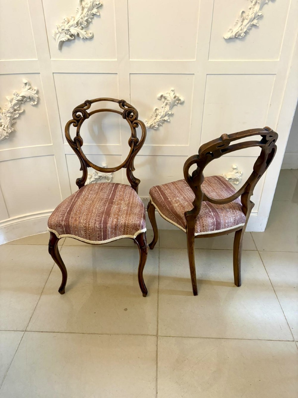 A set of four Victorian walnut balloon back dining chairs featuring carved openwork backrests, cabriole front legs, and patterned rose-coloured upholstered seats. View IV