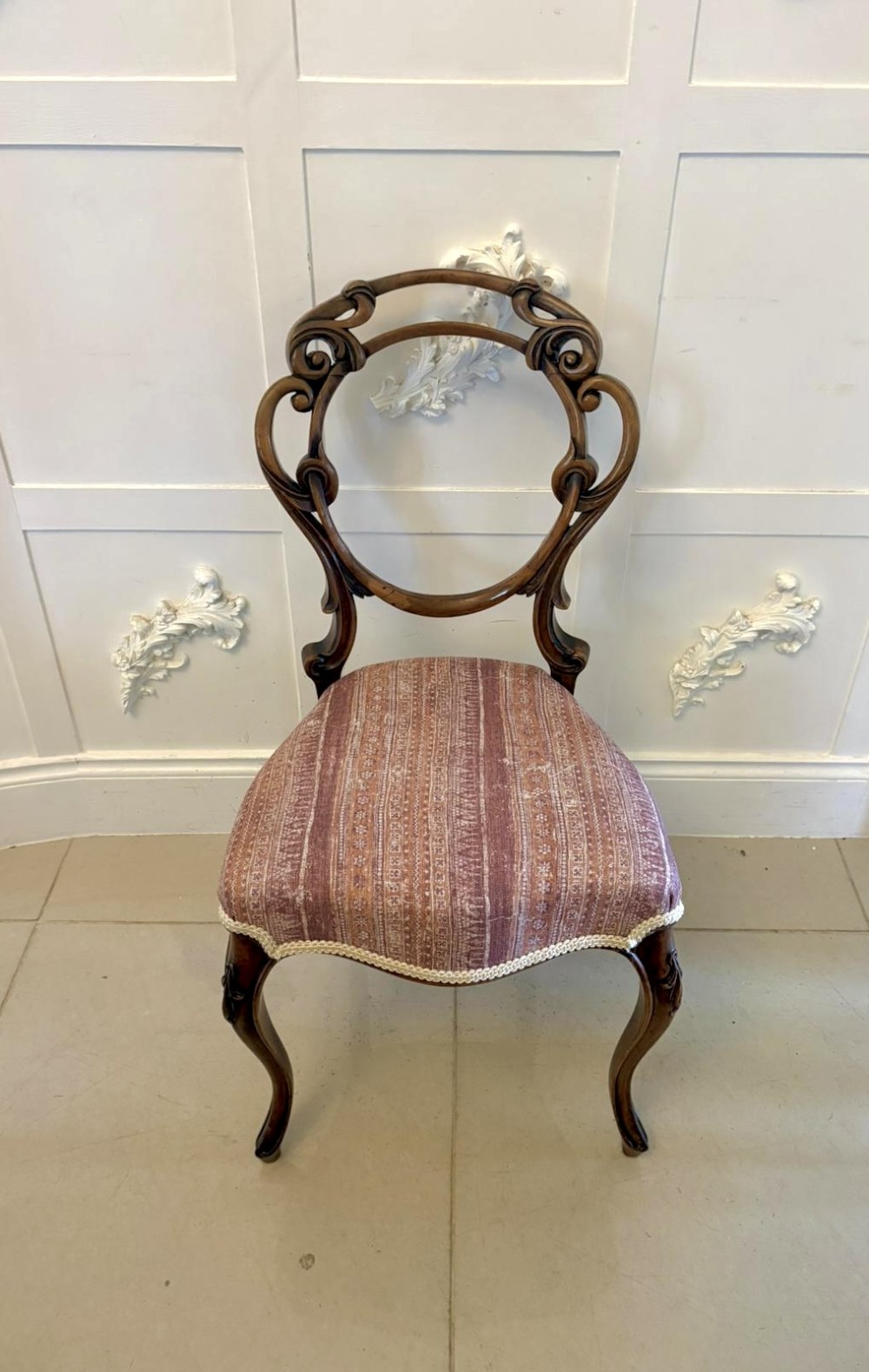A set of four Victorian walnut balloon back dining chairs featuring carved openwork backrests, cabriole front legs, and patterned rose-coloured upholstered seats. View V