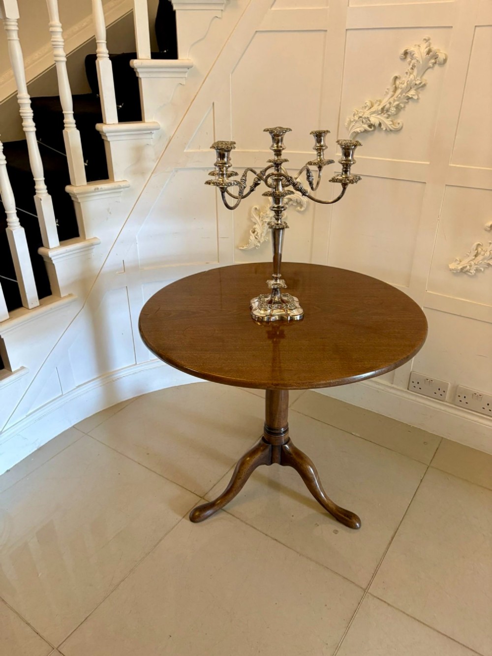 An 18th-century Georgian circular mahogany tilt-top table shown with its surface tilted vertically on a turned column with three cabriole legs. View II