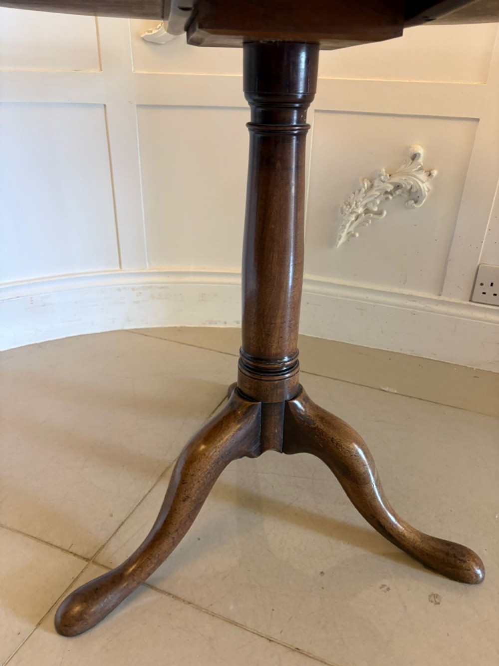 An 18th-century Georgian circular mahogany tilt-top table shown with its surface tilted vertically on a turned column with three cabriole legs. View III