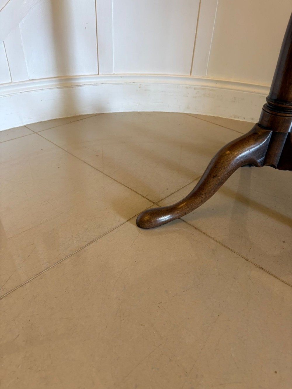 An 18th-century Georgian circular mahogany tilt-top table shown with its surface tilted vertically on a turned column with three cabriole legs. View V