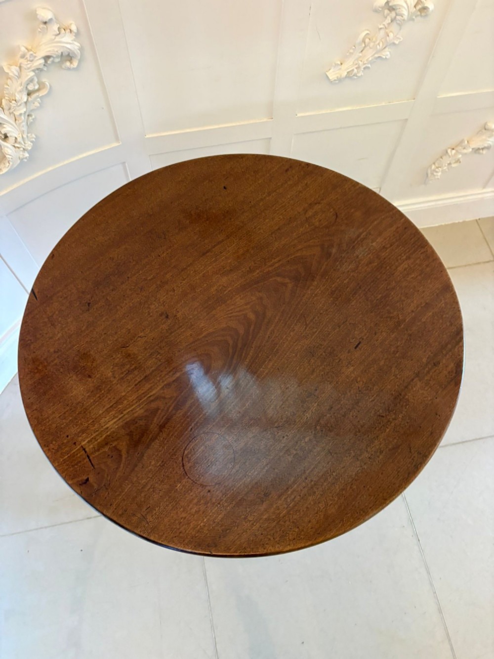 An 18th-century Georgian circular mahogany tilt-top table shown with its surface tilted vertically on a turned column with three cabriole legs. View VII