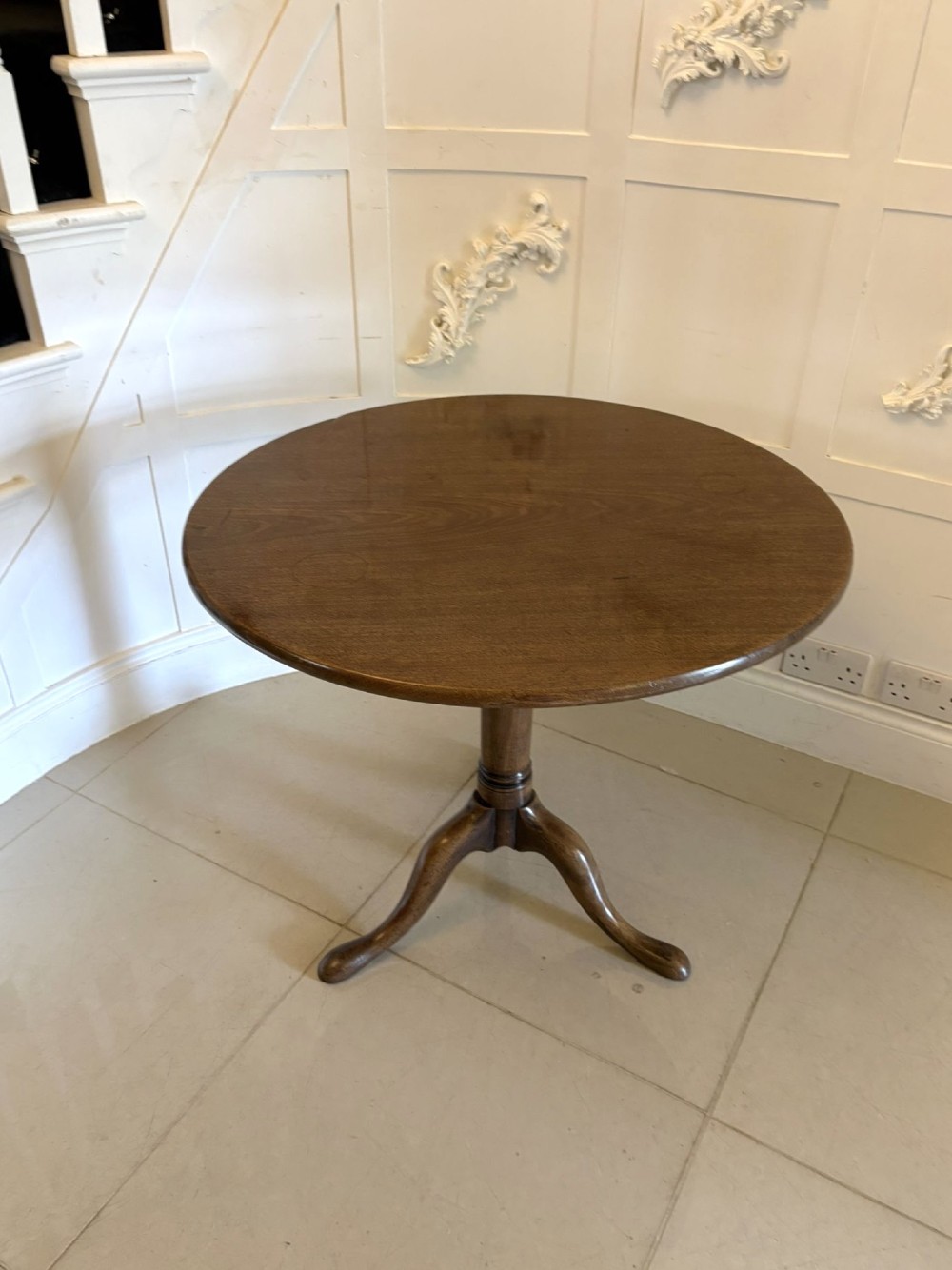 An 18th-century Georgian circular mahogany tilt-top table shown with its surface tilted vertically on a turned column with three cabriole legs. View VIII