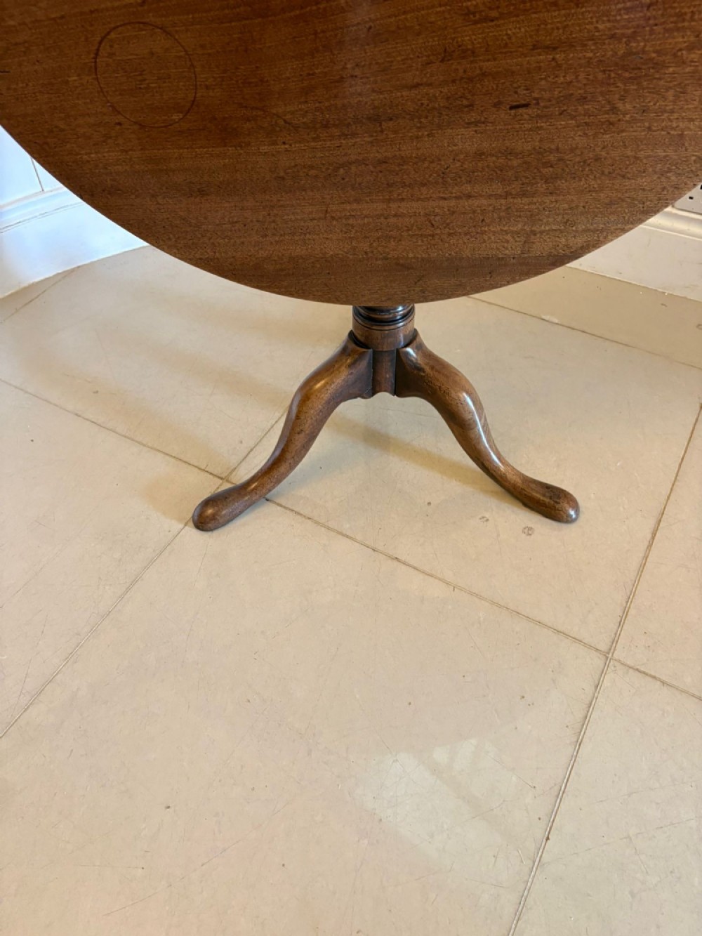 An 18th-century Georgian circular mahogany tilt-top table shown with its surface tilted vertically on a turned column with three cabriole legs. View IX
