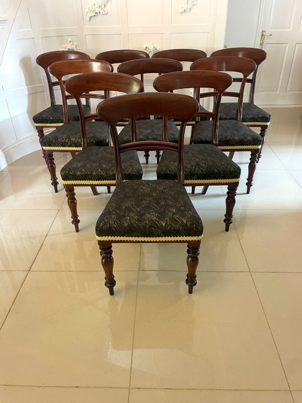 A set of ten Victorian mahogany dining chairs with curved crest rails, turned front legs, and dark pattern upholstered seats. View III