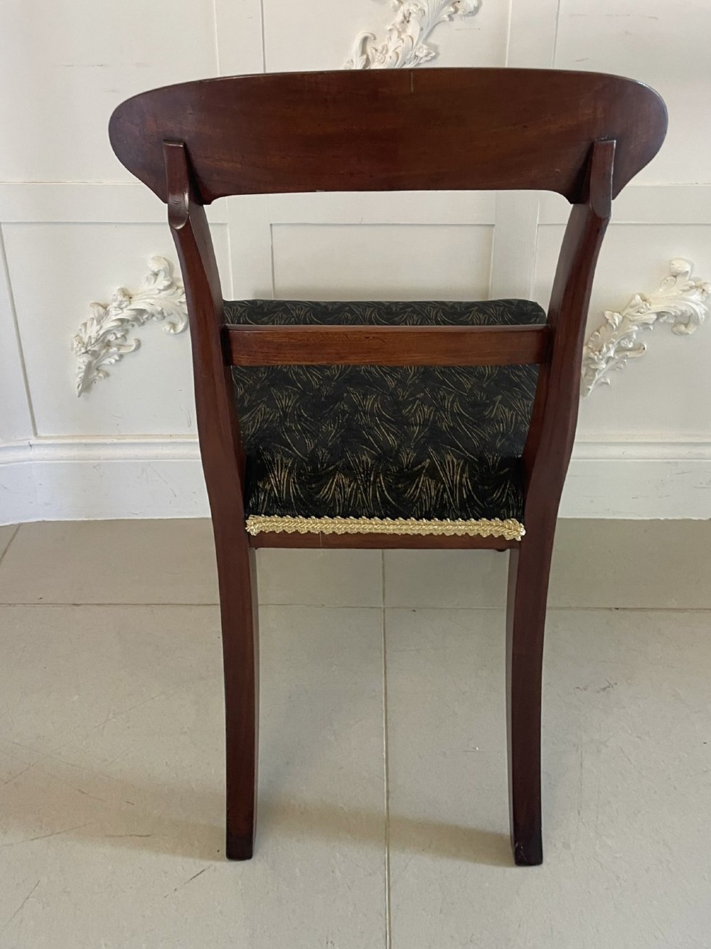 A set of ten Victorian mahogany dining chairs with curved crest rails, turned front legs, and dark pattern upholstered seats. View V