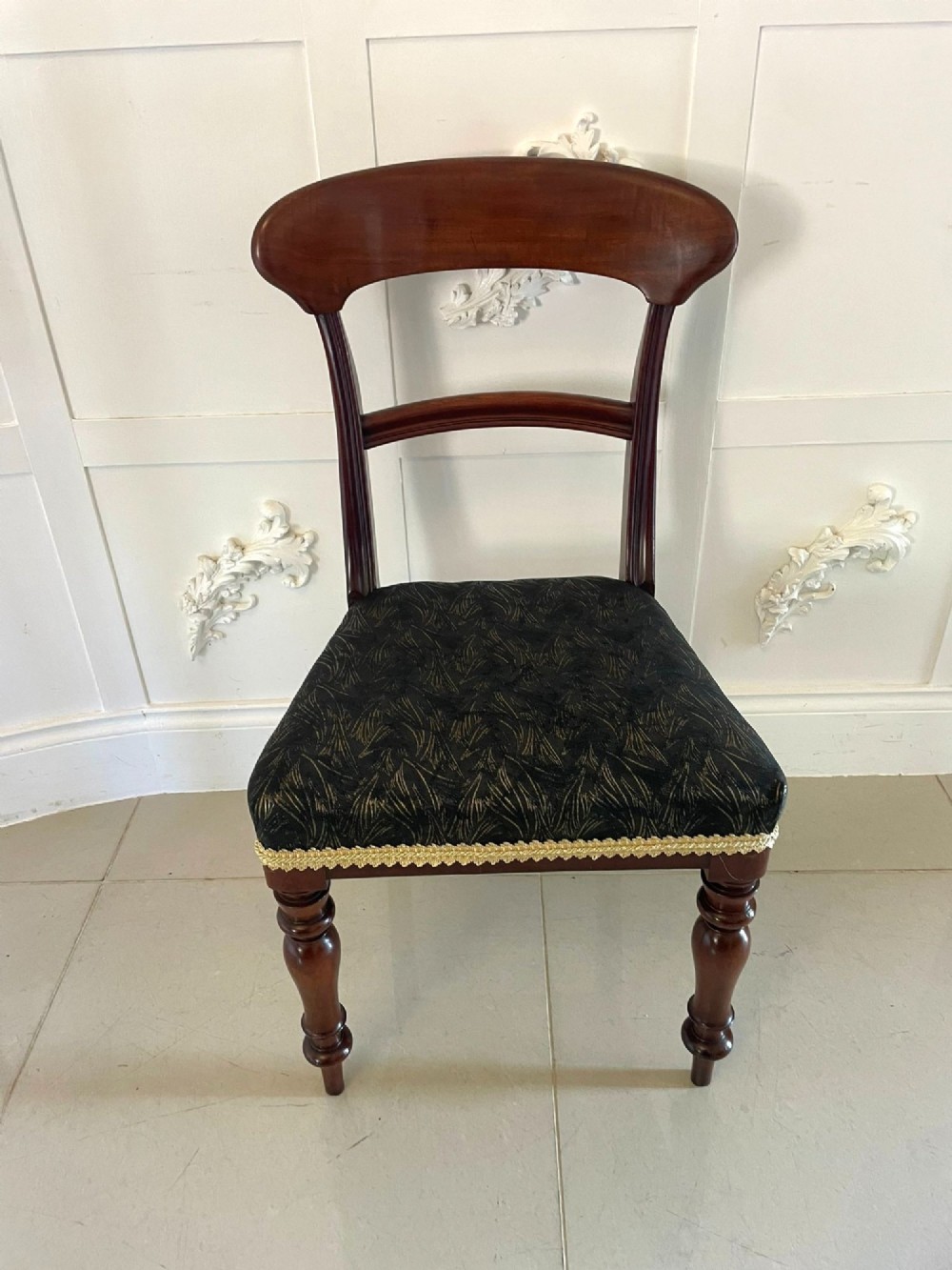 A set of ten Victorian mahogany dining chairs with curved crest rails, turned front legs, and dark pattern upholstered seats. View VIII