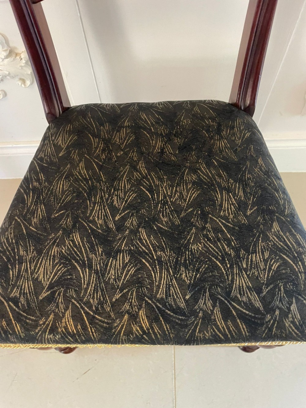 A set of ten Victorian mahogany dining chairs with curved crest rails, turned front legs, and dark pattern upholstered seats. View IX
