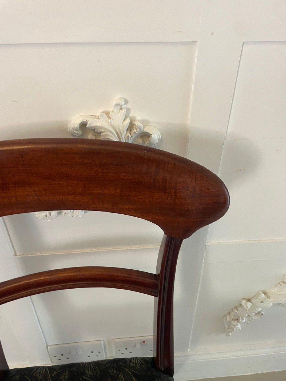 A set of ten Victorian mahogany dining chairs with curved crest rails, turned front legs, and dark pattern upholstered seats. View X
