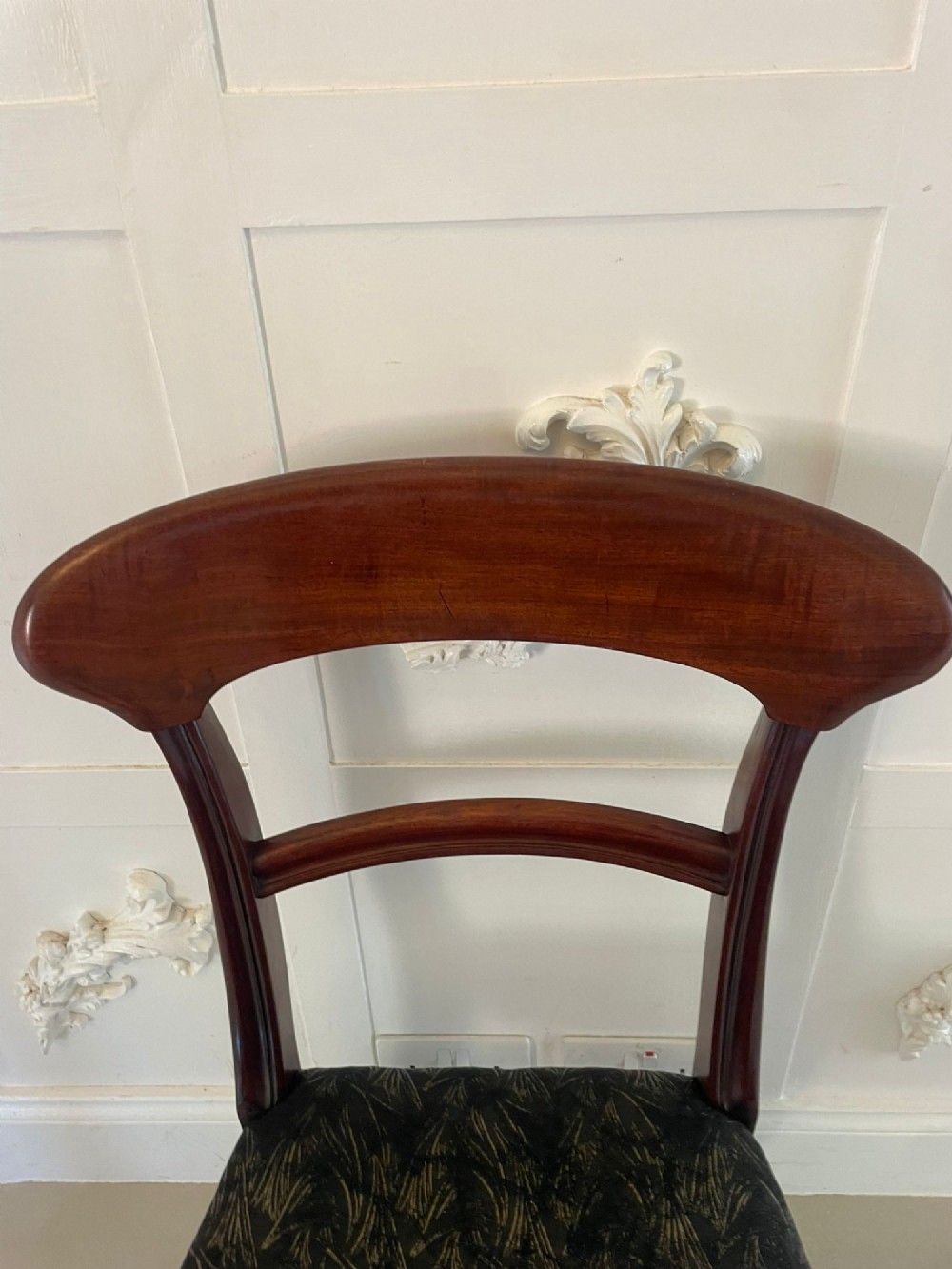 A set of ten Victorian mahogany dining chairs with curved crest rails, turned front legs, and dark pattern upholstered seats. View XI