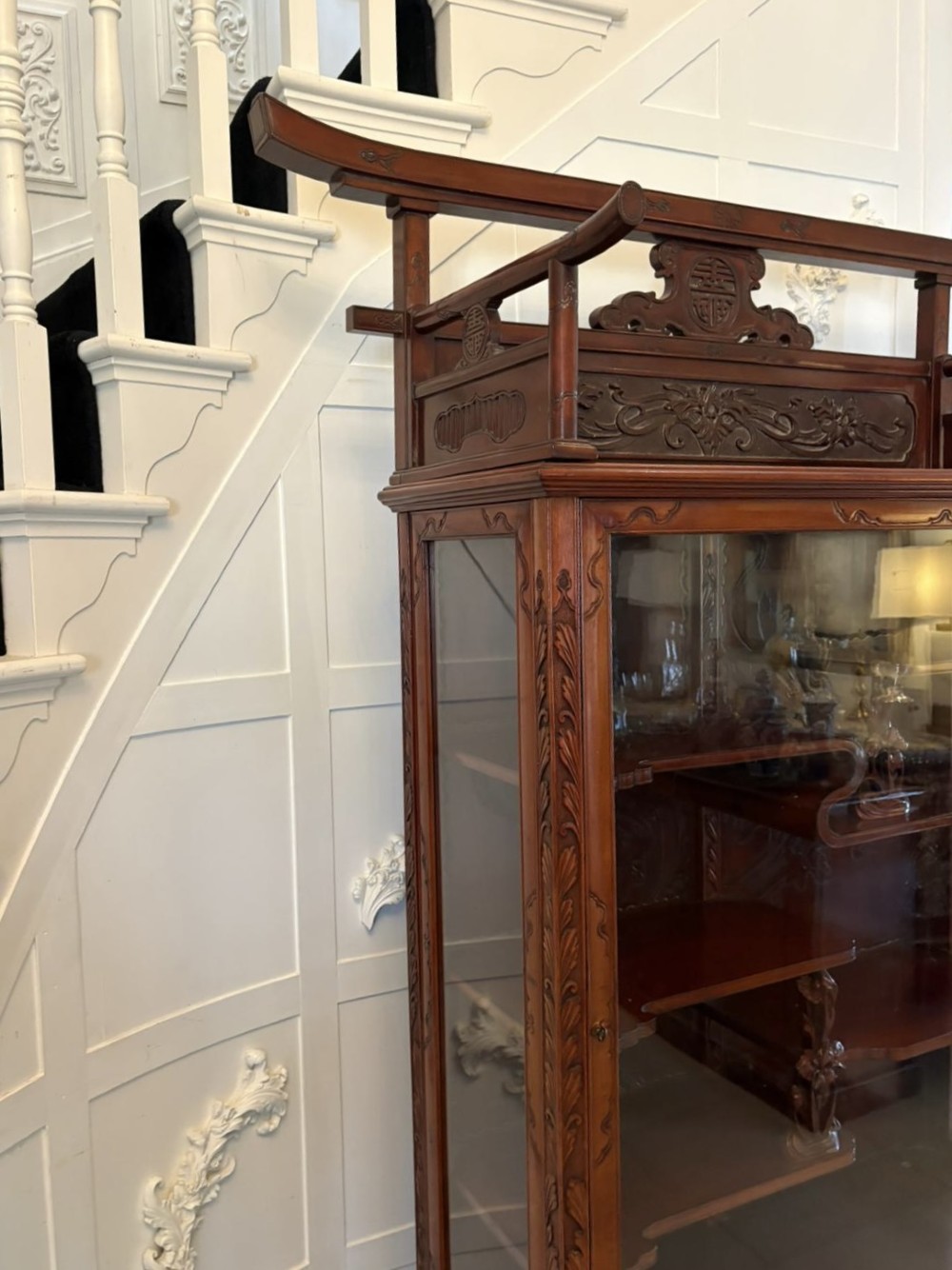 A carved reddish-brown hardwood display cabinet featuring a pagoda cresting, glass door, asymmetrical interior shelves, lower drawers, and cabriole legs. View XIV