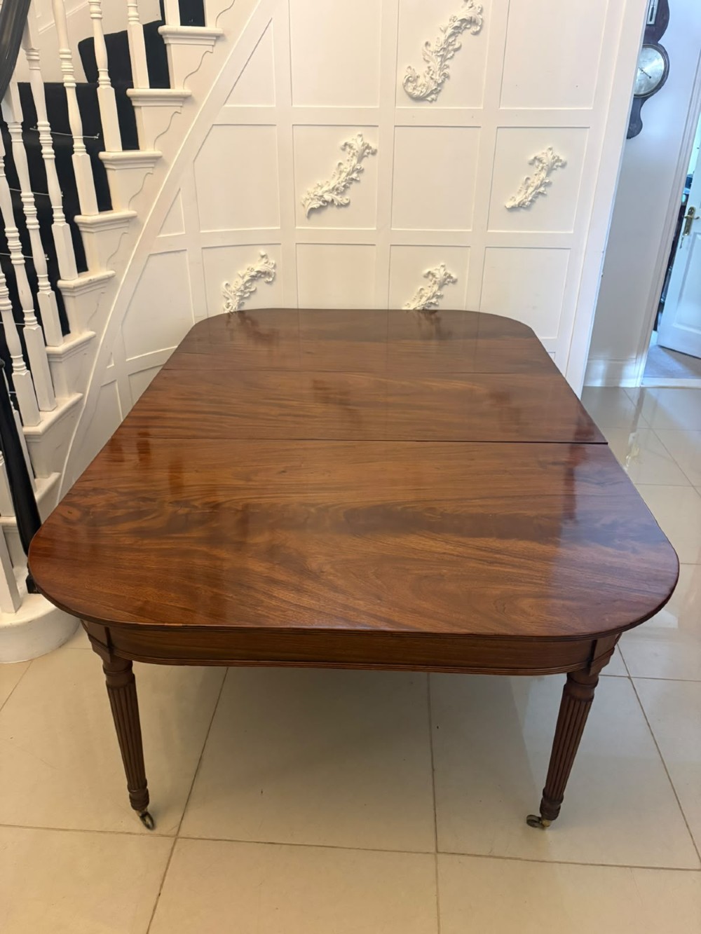 A long Regency extending dining table crafted from polished figured mahogany with reeded legs set on brass castors. View III