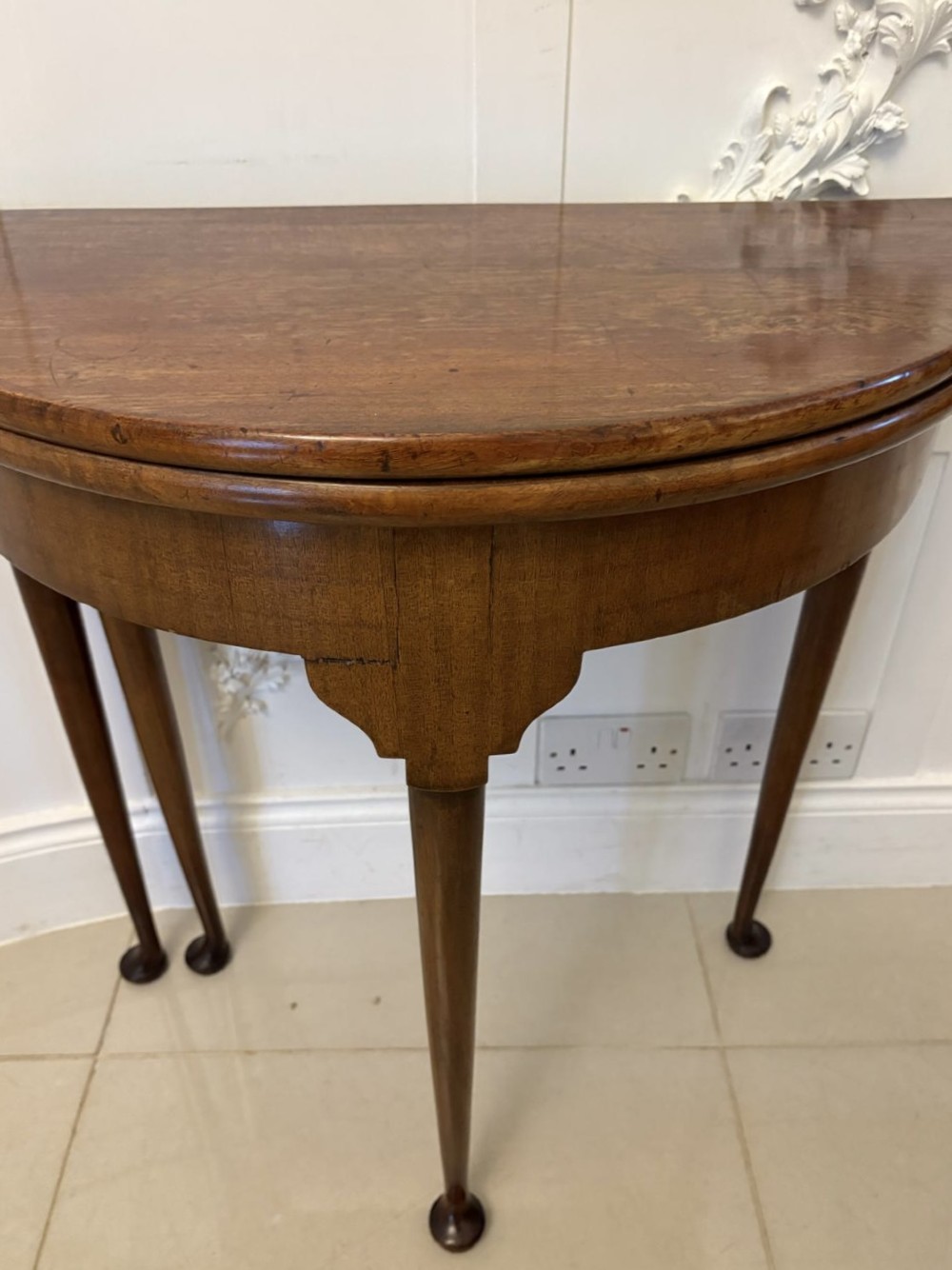 An antique warm brown mahogany demi-lune card table featuring tapered legs with pad feet and a fold-over top. View VI