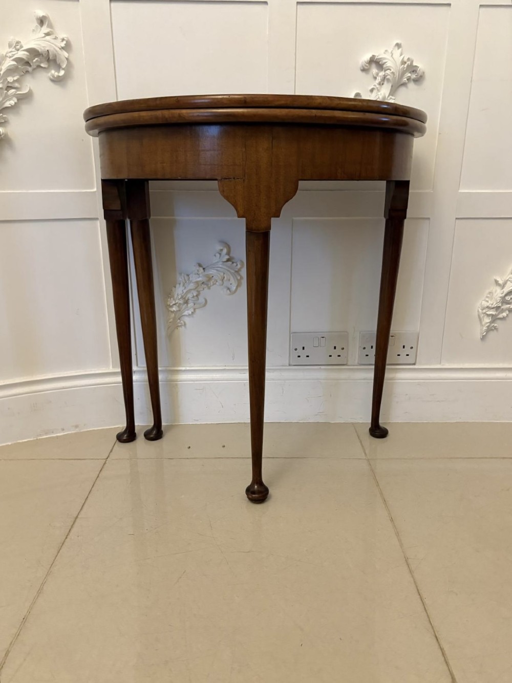 An antique warm brown mahogany demi-lune card table featuring tapered legs with pad feet and a fold-over top. View VII