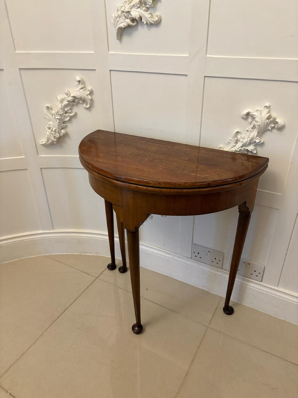 An antique warm brown mahogany demi-lune card table featuring tapered legs with pad feet and a fold-over top. View IX