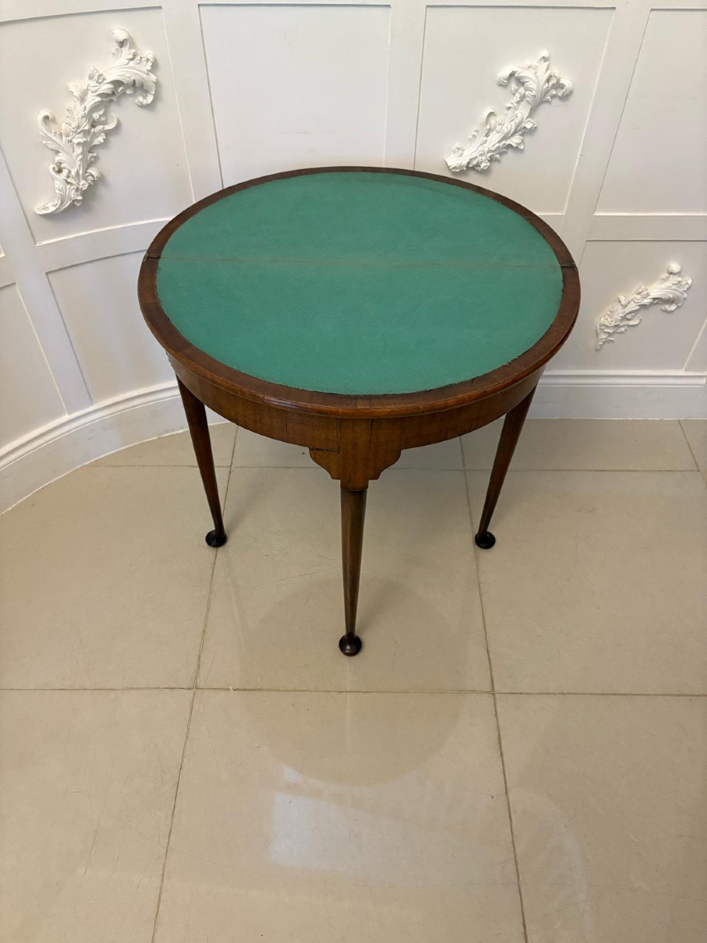 An antique warm brown mahogany demi-lune card table featuring tapered legs with pad feet and a fold-over top. View XII