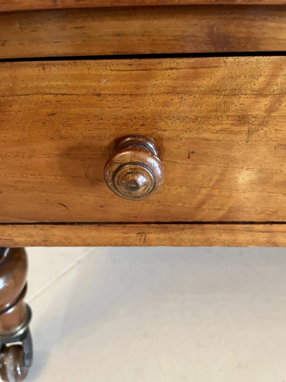 A Victorian figured walnut Canterbury featuring multiple vertical turned spindles, corner finials, a lower base drawer with two knobs, and brass castors. View IX