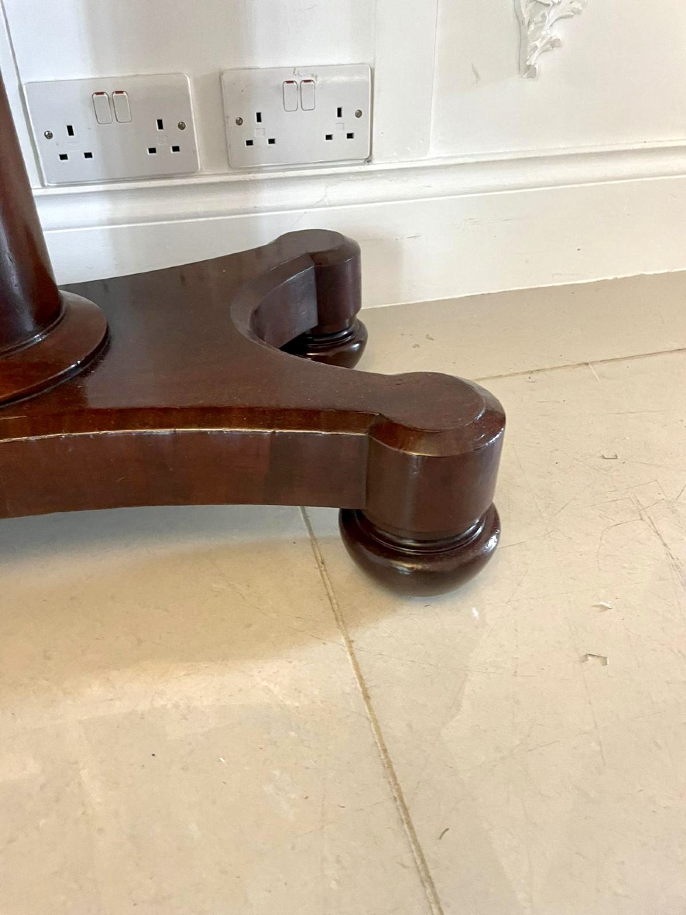 A Victorian mahogany card table featuring a rectangular fold-over top, carved scroll apron brackets, and a central cylindrical pedestal on a four-point plinth base. View VI
