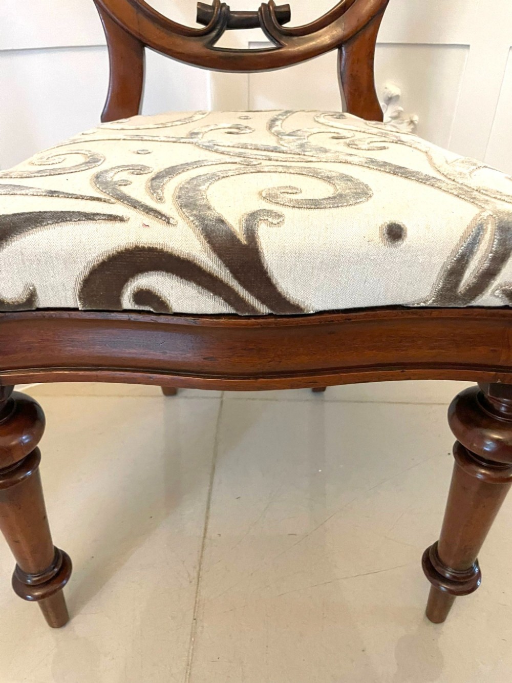 A set of six Victorian mahogany dining chairs featuring rounded balloon backrests, carved mid-rails, patterned upholstery, and turned front legs. View IV