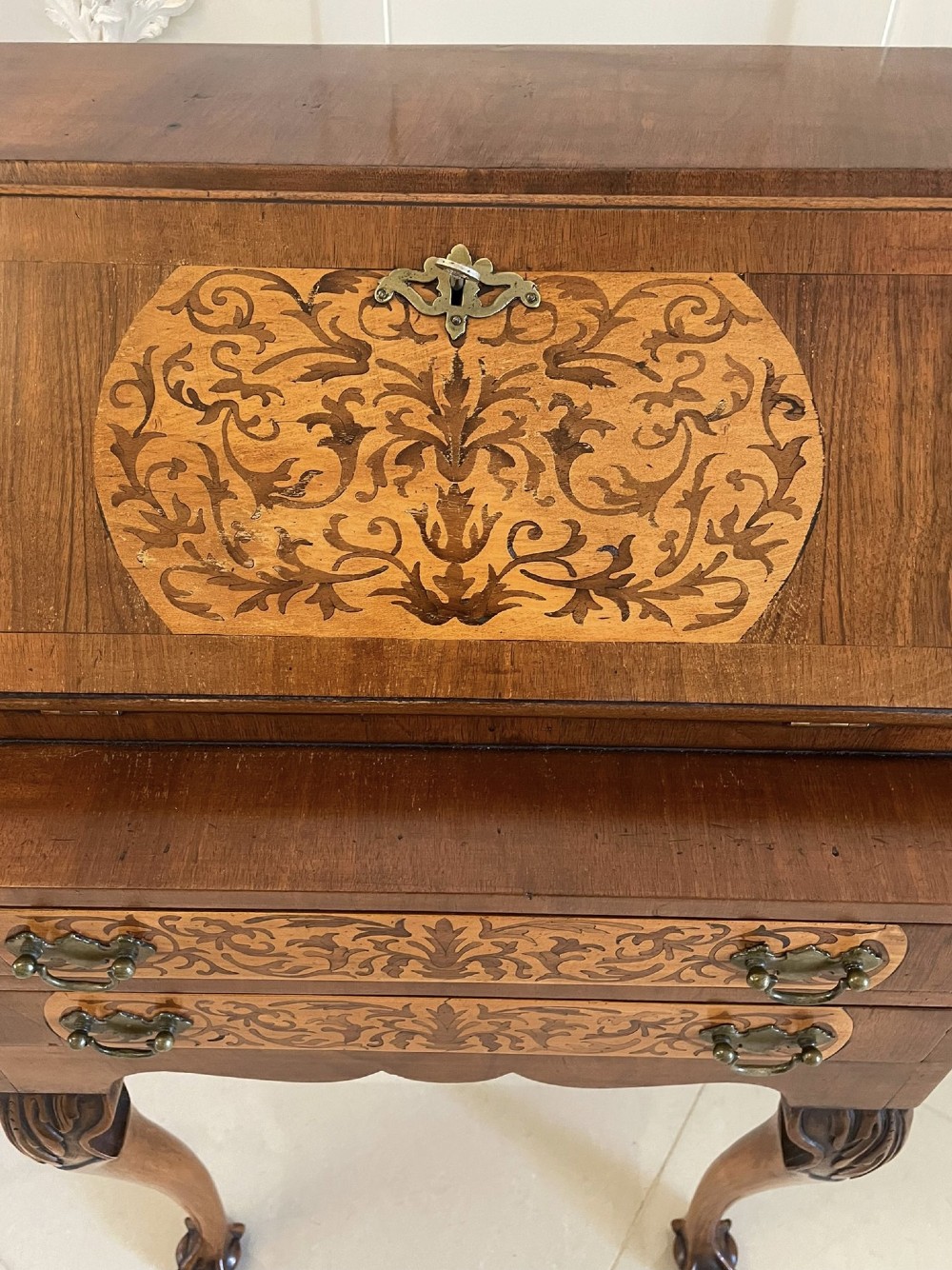 An antique burr walnut slant-front bureau featuring central floral marquetry inlay, two drawers, and carved cabriole legs with claw and ball feet. View II