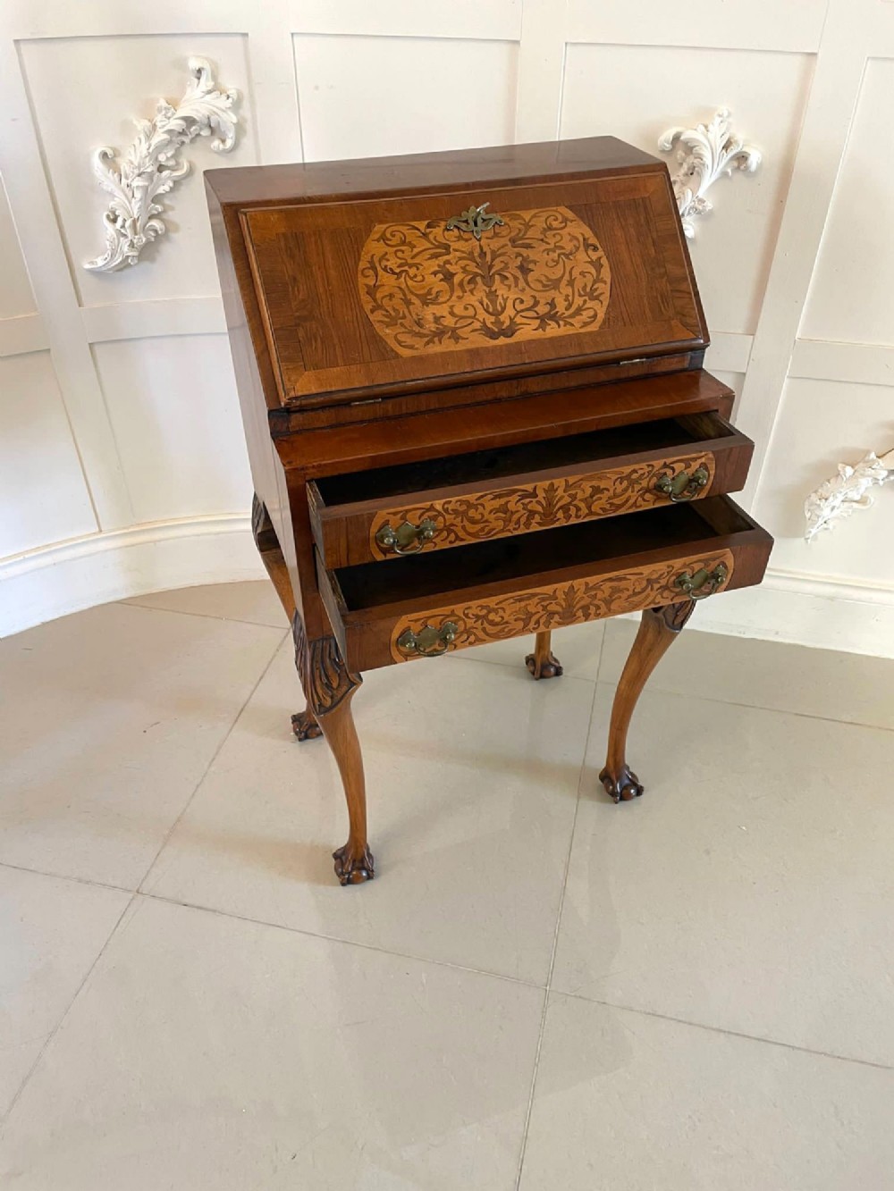 An antique burr walnut slant-front bureau featuring central floral marquetry inlay, two drawers, and carved cabriole legs with claw and ball feet. View V