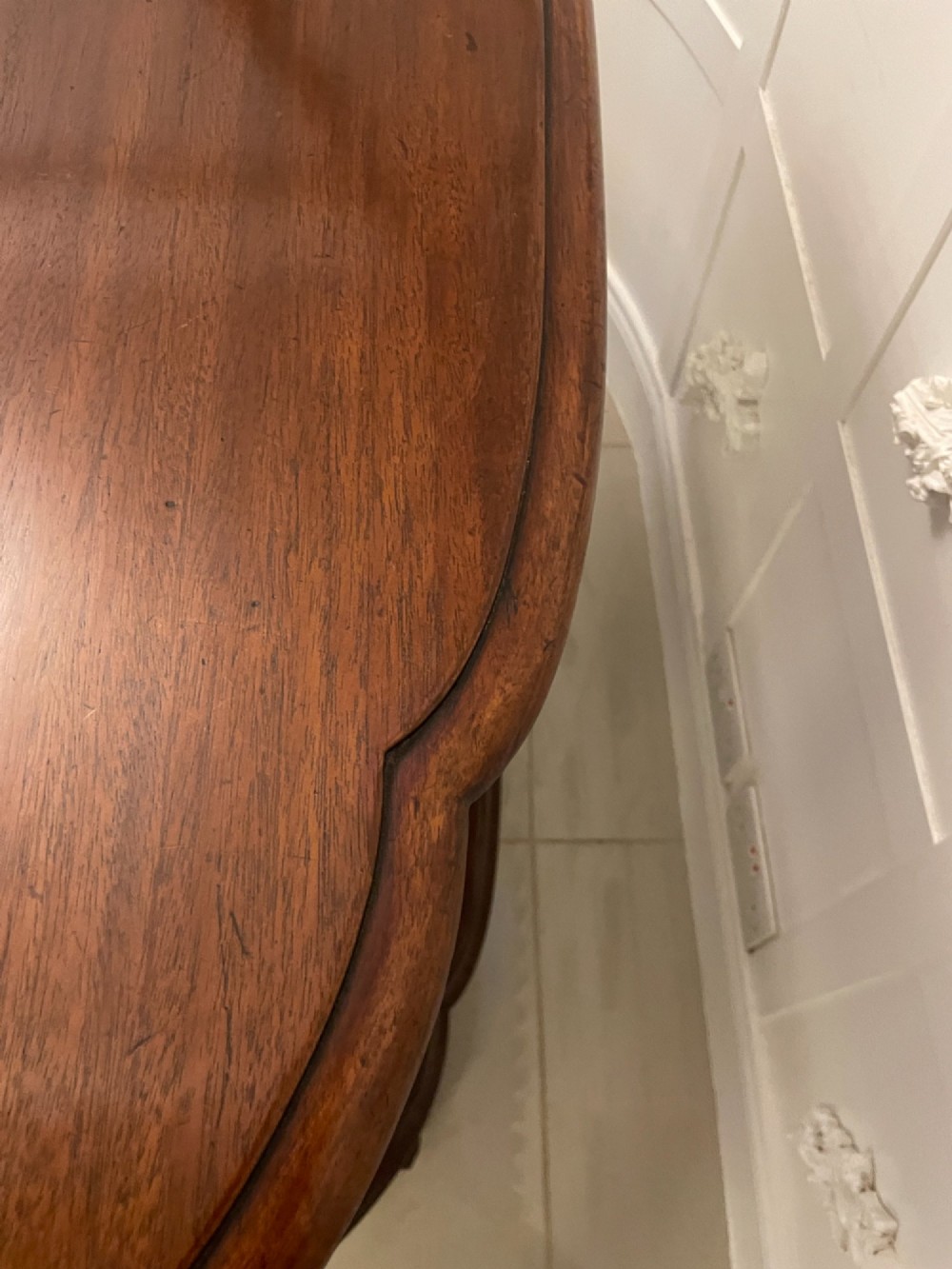 A two-tiered oval mahogany console table featuring carved column supports, a smooth polished finish, and castors on scroll feet. View II