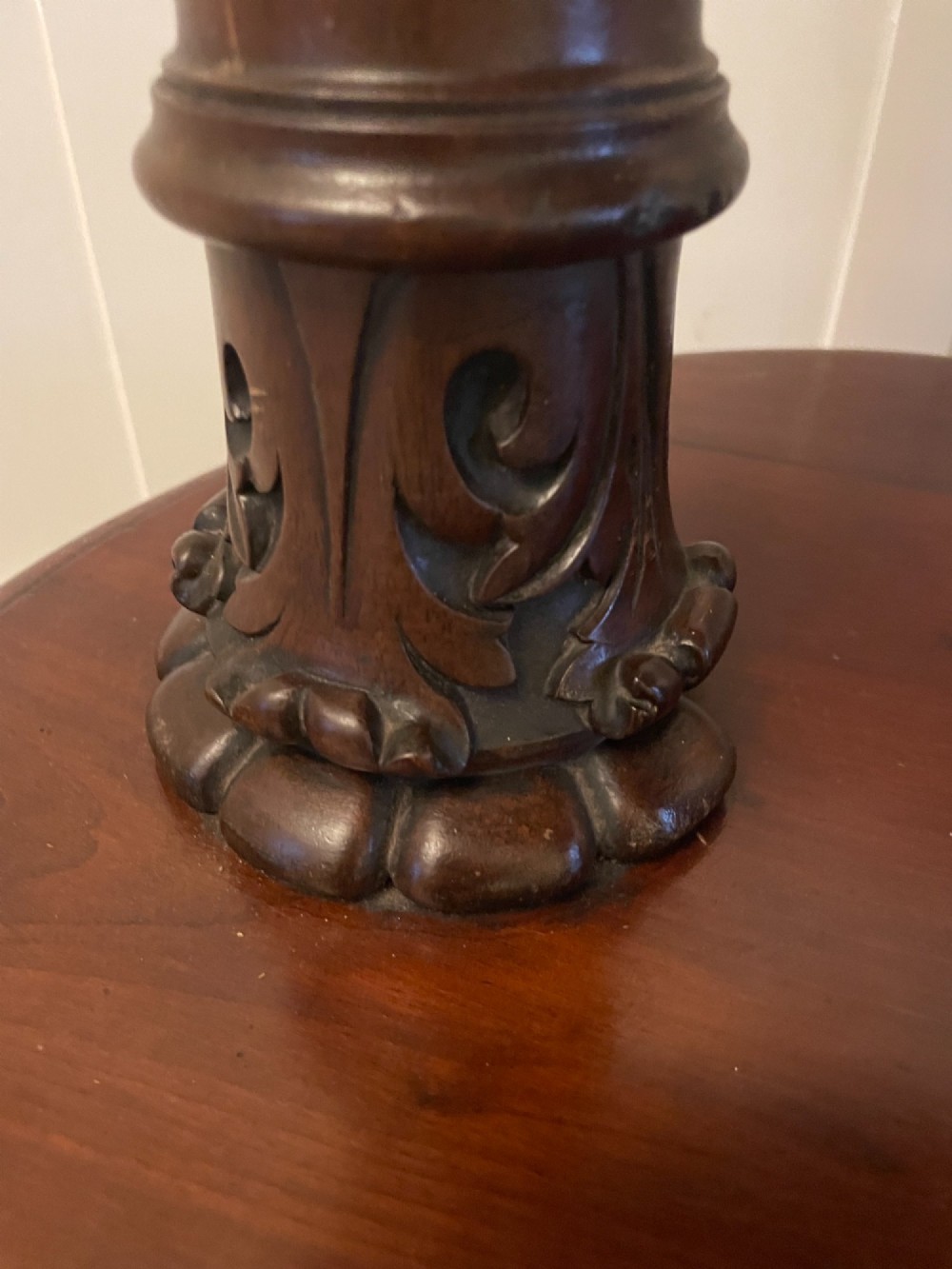 A two-tiered oval mahogany console table featuring carved column supports, a smooth polished finish, and castors on scroll feet. View IV