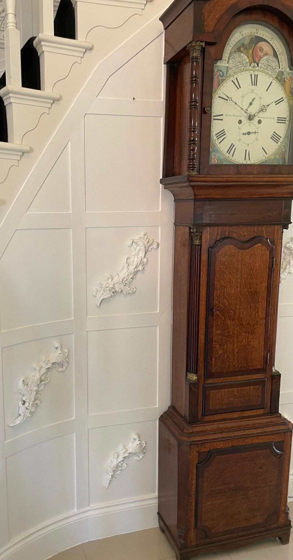 An antique George III oak and mahogany longcase clock with a swan-neck pediment, reeded columns, and a painted moon phase dial. View IV