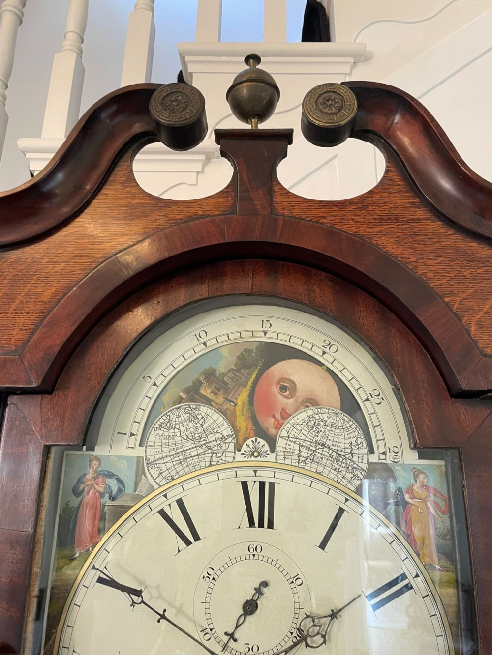 An antique George III oak and mahogany longcase clock with a swan-neck pediment, reeded columns, and a painted moon phase dial. View XII