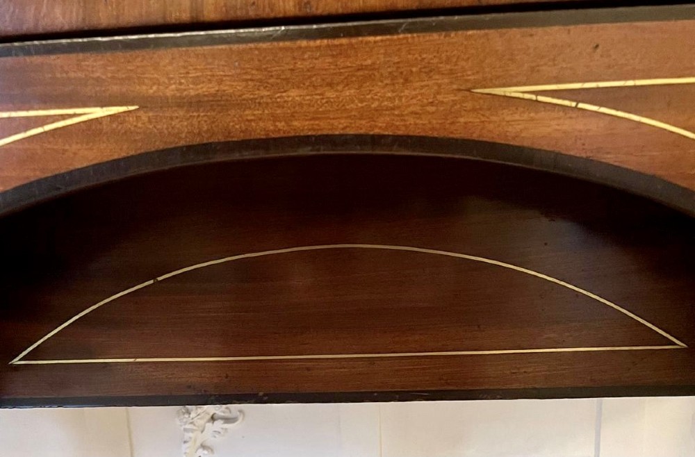 A Regency period mahogany breakfront sideboard featuring brass inlay motifs, a central drawer flanked by cupboards, turned legs, and brass castors. View IV