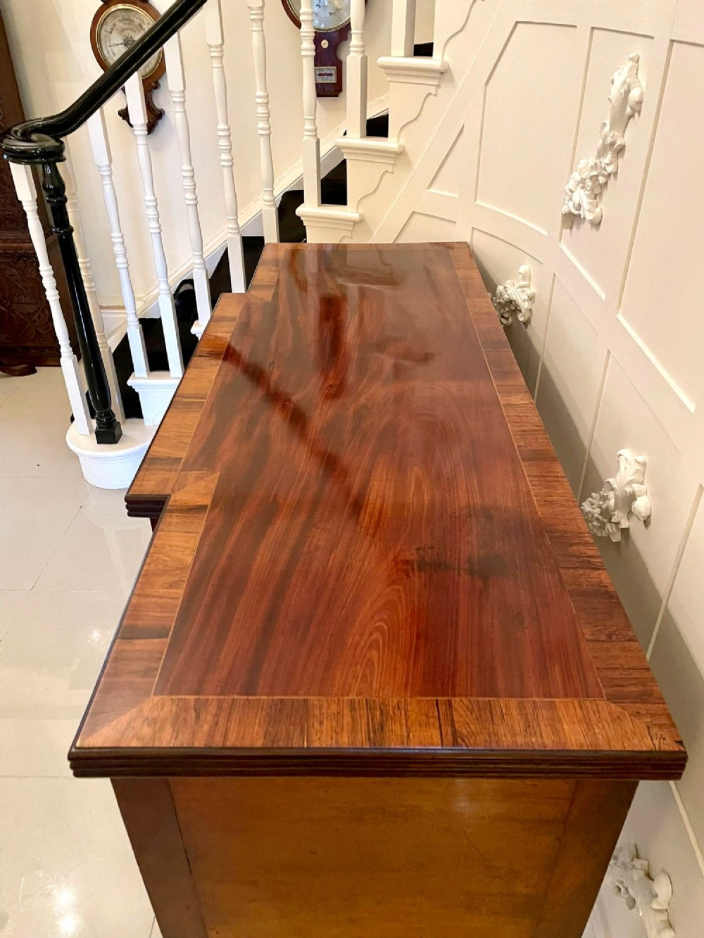 A Regency period mahogany breakfront sideboard featuring brass inlay motifs, a central drawer flanked by cupboards, turned legs, and brass castors. View VII