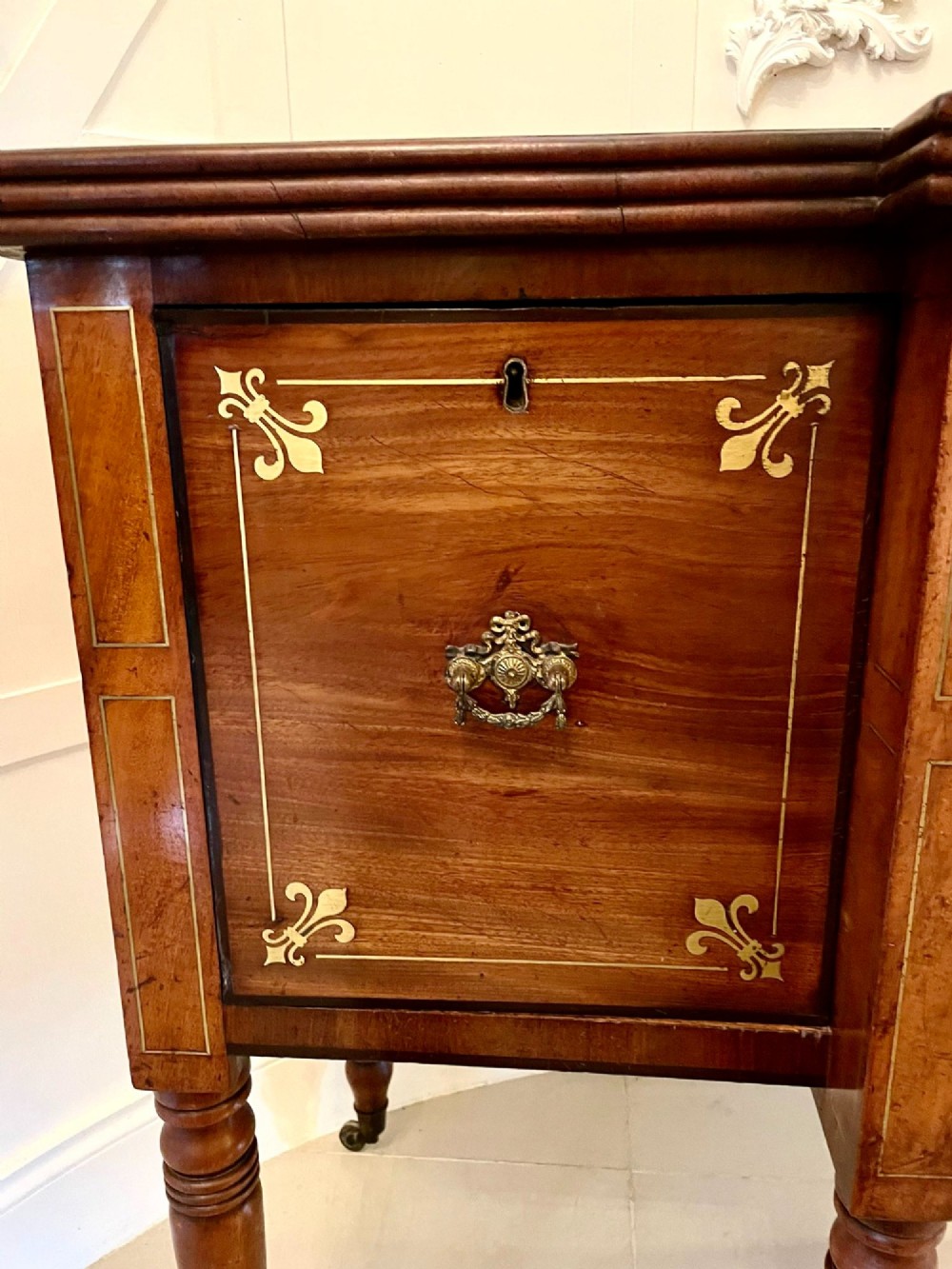 A Regency period mahogany breakfront sideboard featuring brass inlay motifs, a central drawer flanked by cupboards, turned legs, and brass castors. View VIII