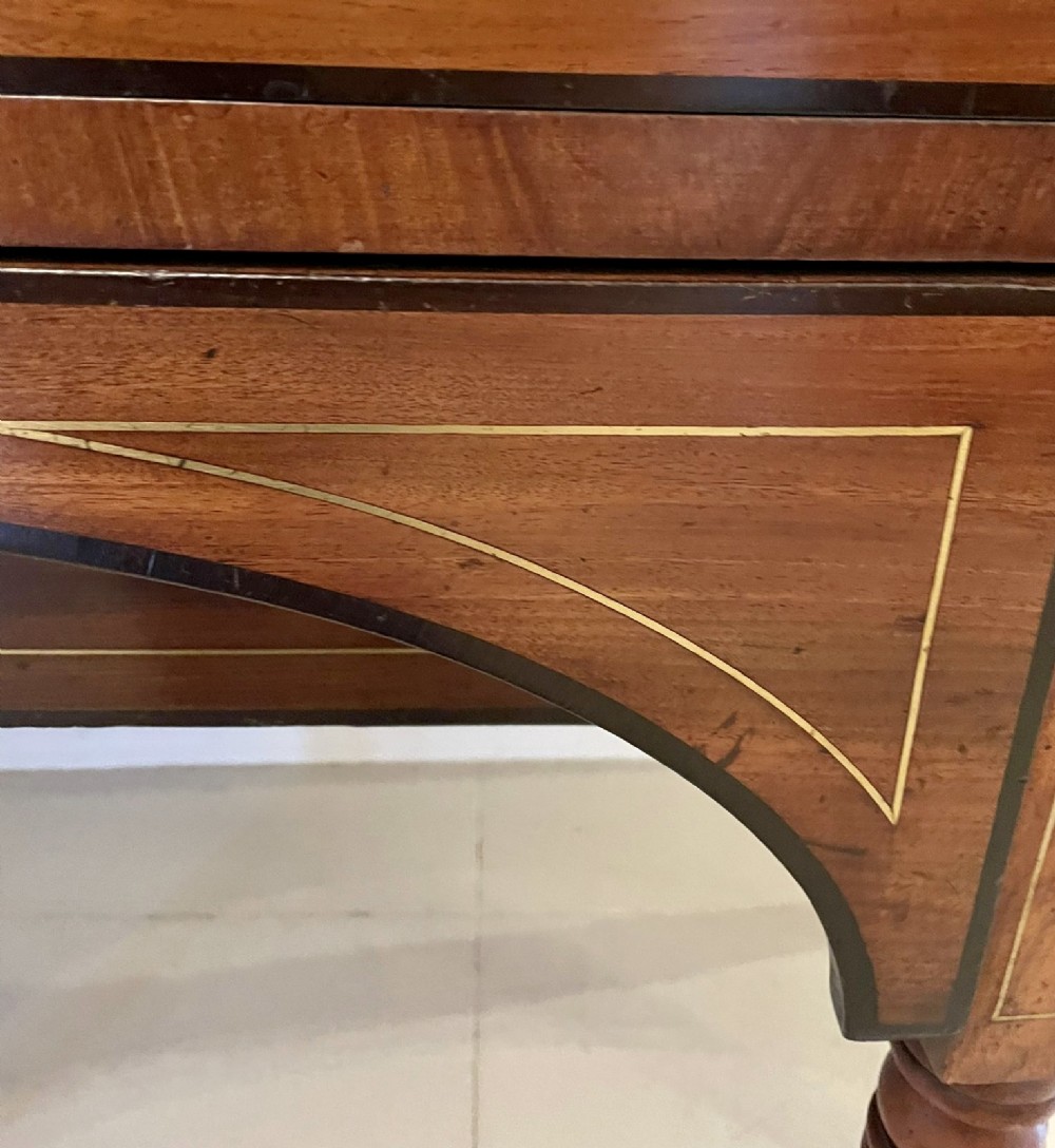 A Regency period mahogany breakfront sideboard featuring brass inlay motifs, a central drawer flanked by cupboards, turned legs, and brass castors. View XI