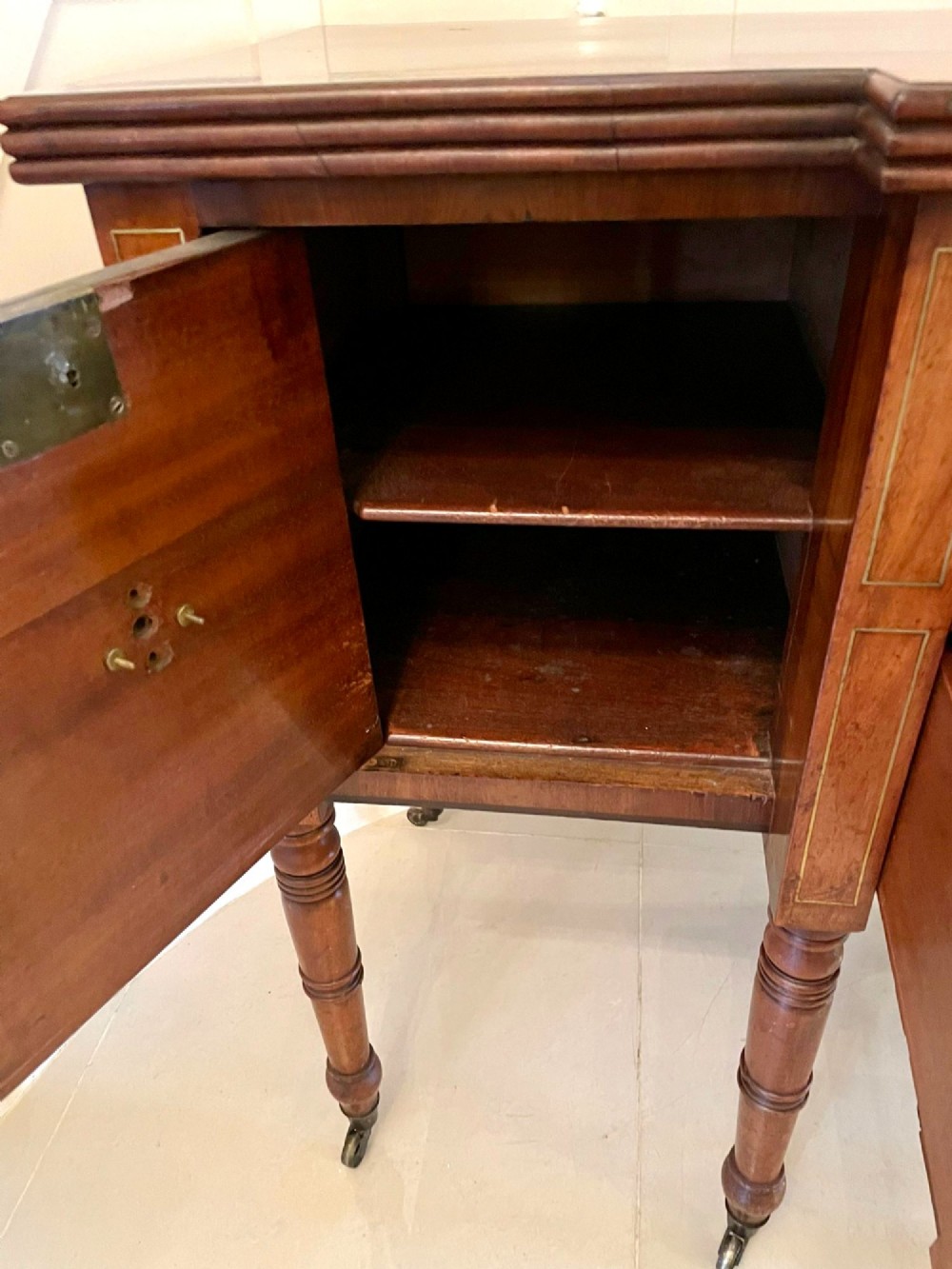 A Regency period mahogany breakfront sideboard featuring brass inlay motifs, a central drawer flanked by cupboards, turned legs, and brass castors. View XIII