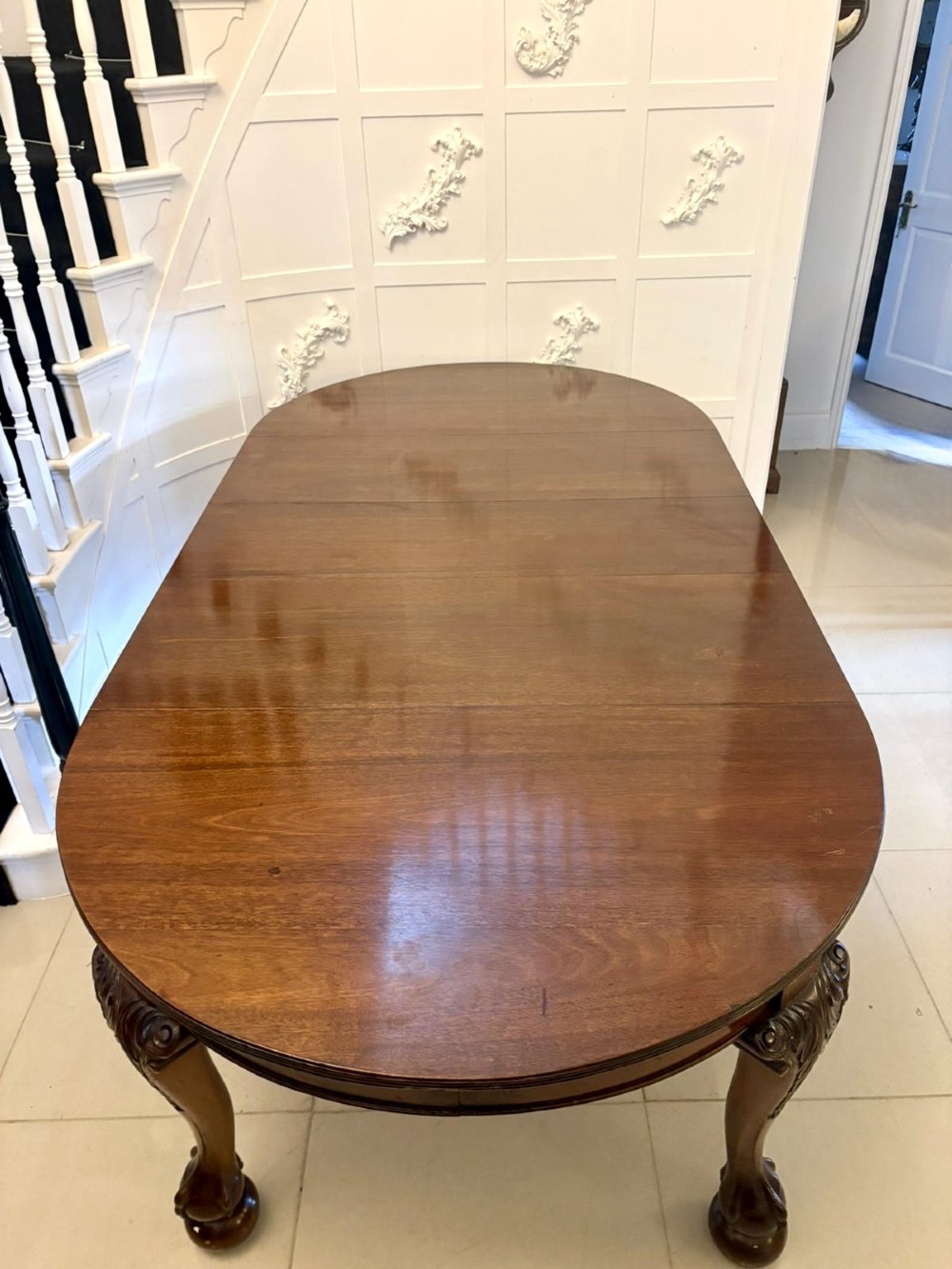 A large Victorian extending mahogany dining table featuring rounded ends and hand-carved cabriole legs with ball and claw feet.