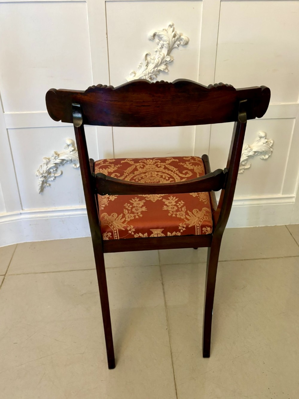 A set of six Regency carved rosewood dining chairs featuring curved backrests with scroll details, turned front legs, and pattern-upholstered seats. View III
