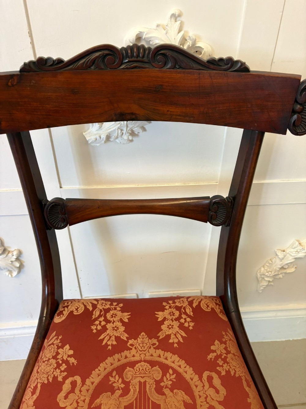 A set of six Regency carved rosewood dining chairs featuring curved backrests with scroll details, turned front legs, and pattern-upholstered seats. View V