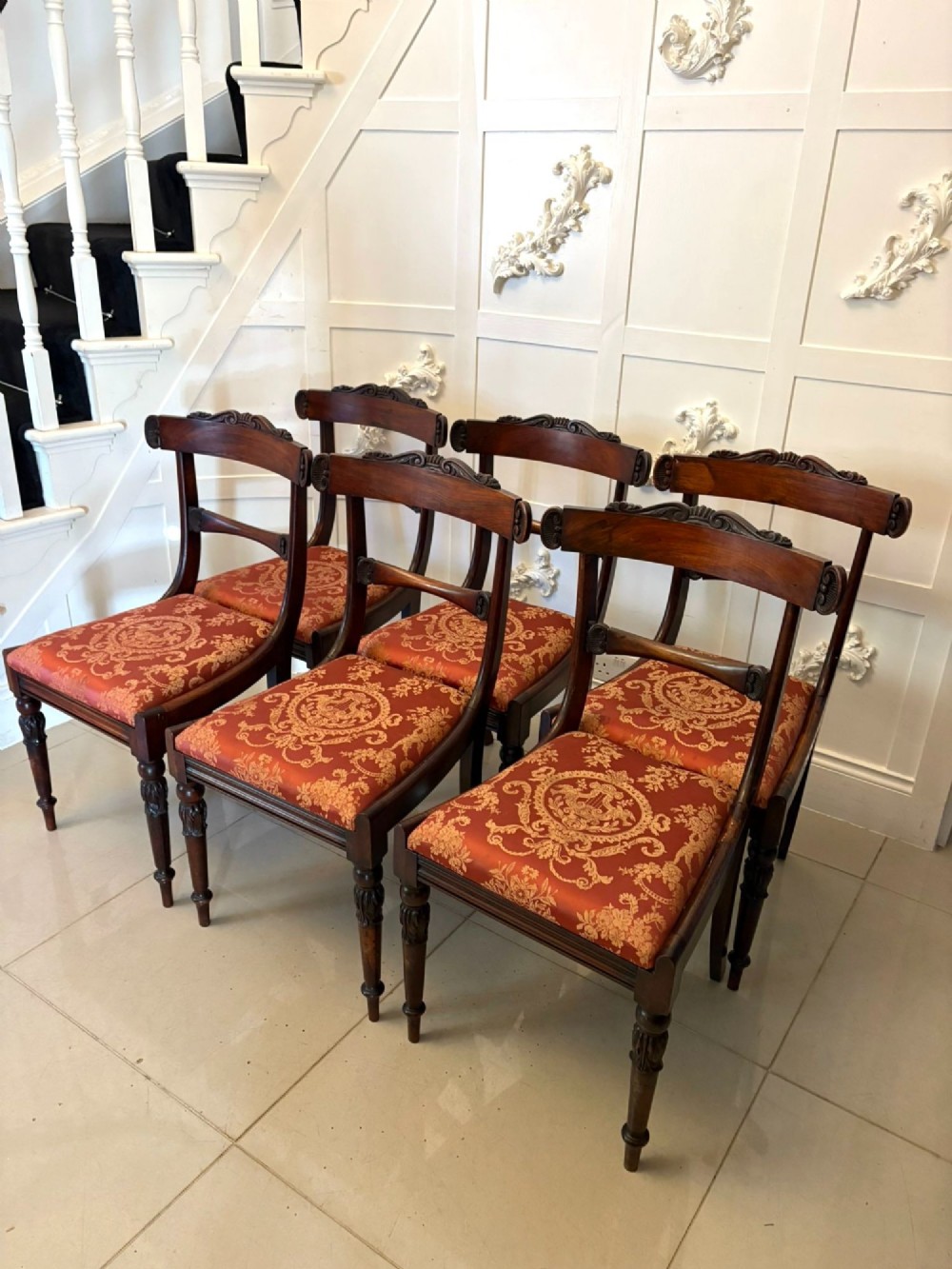 A set of six Regency carved rosewood dining chairs featuring curved backrests with scroll details, turned front legs, and pattern-upholstered seats. View IX