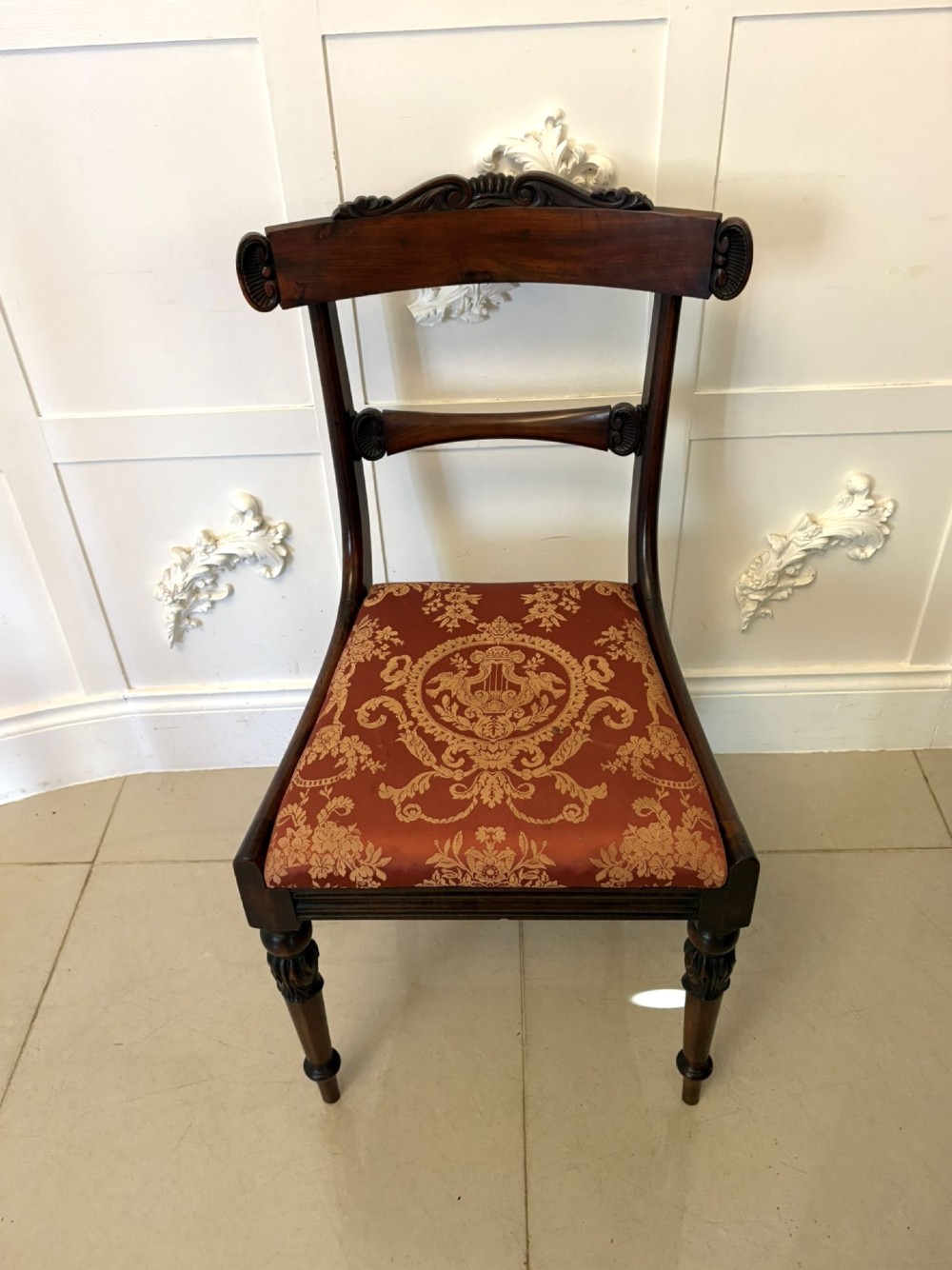 A set of six Regency carved rosewood dining chairs featuring curved backrests with scroll details, turned front legs, and pattern-upholstered seats. View XII